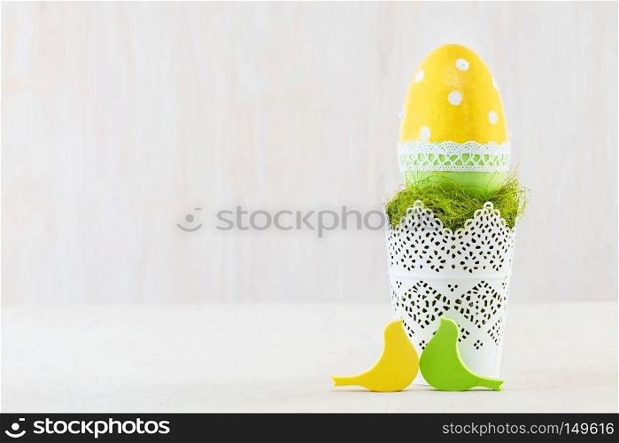 Single easter handmade egg in a decorative pot on wooden table.. Single easter egg in a pot.