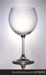 Single empty glass for red wine on reflective surface