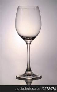 Single empty glass for white wine on reflective surface