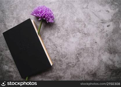 single fake purple flower inside closed notebook stained background