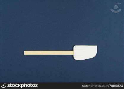 Single kitchen spatula used for baking and cooking in the preparation of food on a blue background with copyspace, overhead view