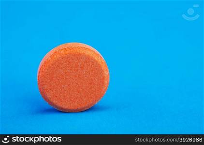 single orange tablet on a blue background