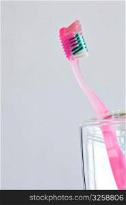 Single pink toothbrush in bathroom toothbrush holder.