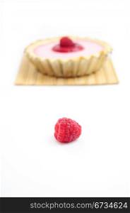 Single raspberry and raspberry tart in the background