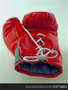Single red and black boxe glove laying over gray background