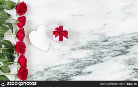 Single red rose with gift box on card with marble stone background in flat lay view