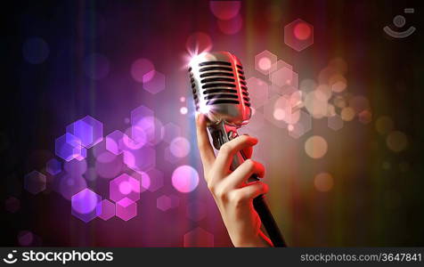 Single retro microphone against colourful background with lights