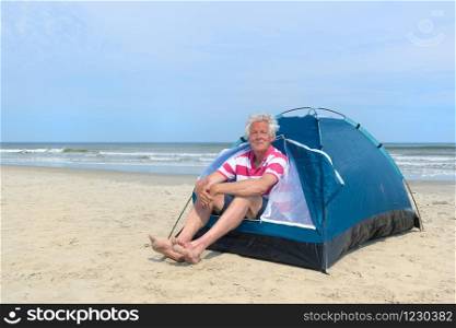 Single senior man camping in shelter at the beach