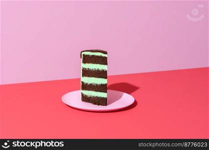 Single slice of cake minimalist on a vibrant-colored table. Homemade layered cake with mint-flavored buttercream and chocolate sponge base.