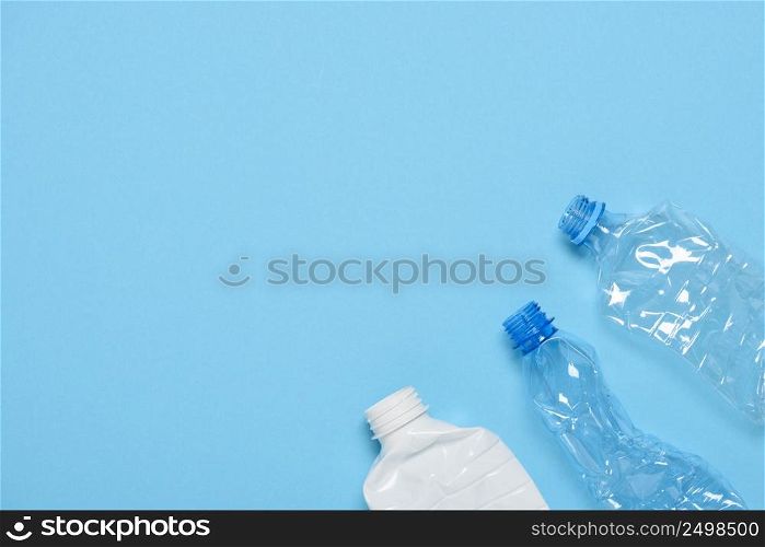 Single use crushed plastic bottles on blue background with copy space. Plastic pollution. Recycle reuse template.