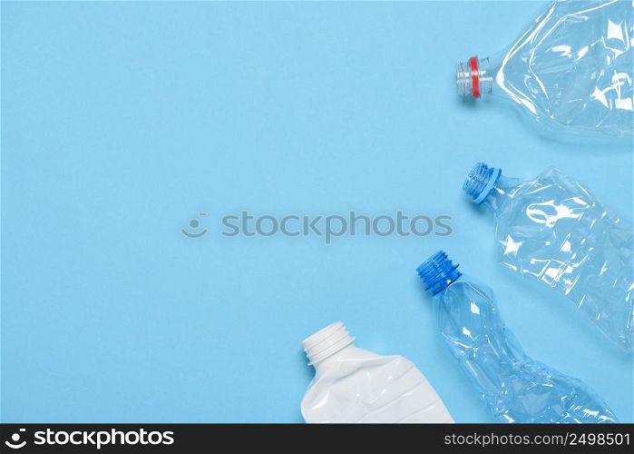 Single use crushed plastic water bottles on blue background with copy space. Plastic pollution. Recycle reuse template.