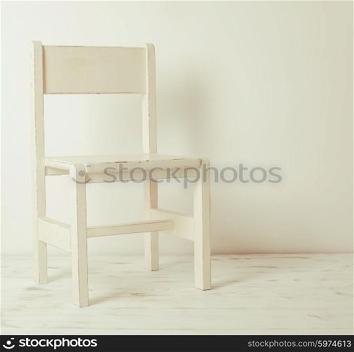 Single white rustic chair standing in an empty room on light wooden parquet floor.. White old-fashioned chair