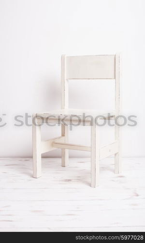 Single white rustic chair standing in an empty room on light wooden parquet floor.. White old-fashioned chair