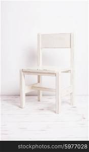 Single white rustic chair standing in an empty room on light wooden parquet floor.. White old-fashioned chair