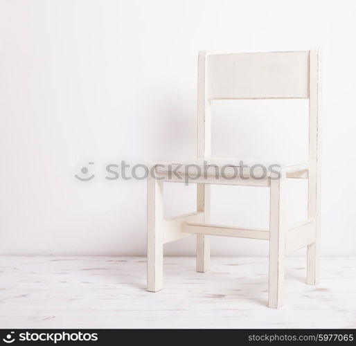 Single white rustic chair standing in an empty room on light wooden parquet floor.. White old-fashioned chair