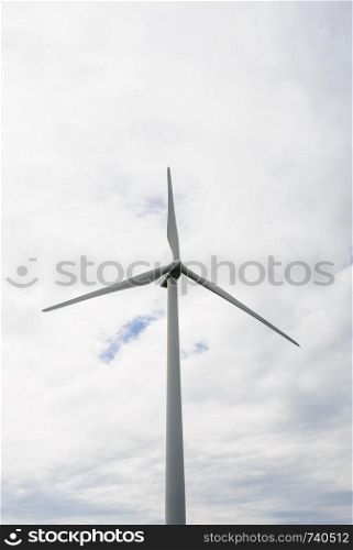 Single wind turbine against cloudy sky.