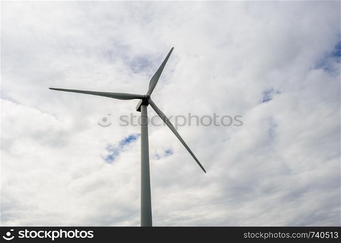 Single wind turbine against cloudy sky.