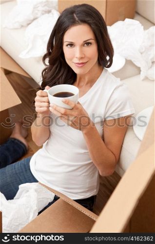 Single Woman Drinking Tea or Coffee Unpacking Boxes Moving House