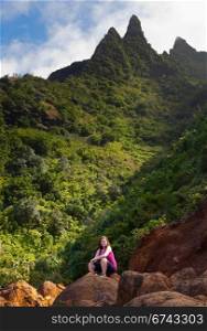 Single woman walker on rock on Kalalau trail along Na Pali coast in Kauai Hawaii