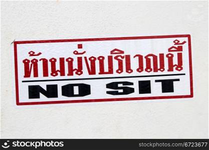 Singn in English and thai - no sit on the wall in Thailand