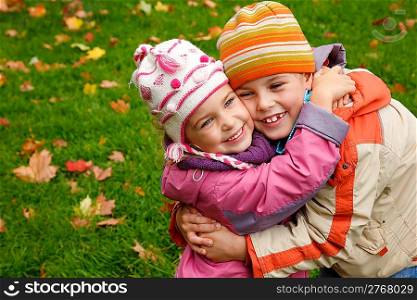 sister and brother embrace in autumnal park