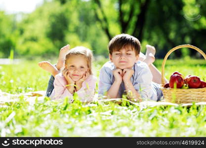 Sister and brother in the park reading a book. Summer weekend outdoors