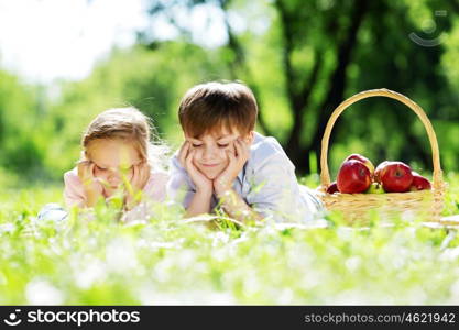 Sister and brother in the park reading a book. Summer weekend outdoors