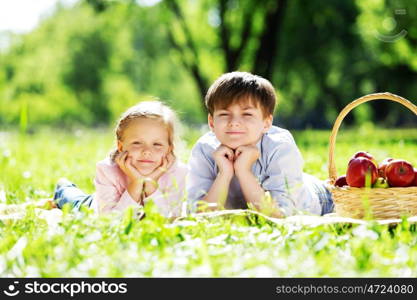 Sister and brother in the park reading a book. Summer weekend outdoors