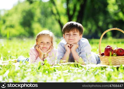 Sister and brother in the park reading a book. Summer weekend outdoors