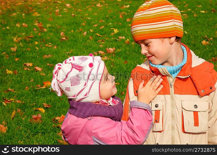sister and brother play in autumnal park