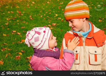 sister and brother play in autumnal park