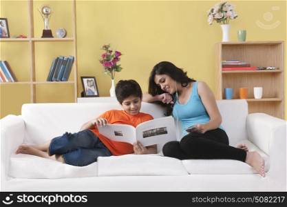 Sister and brother sitting on couch looking into book