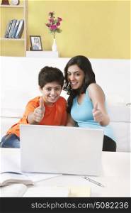 Sister and brother watching laptop showing thumbs up gesture