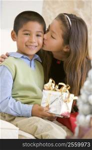 Sister Giving Her Brother A Christmas Present And Kissing Him On The Cheek