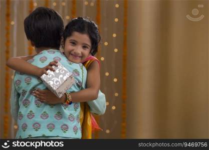 sister hugging brother with gift box in hand