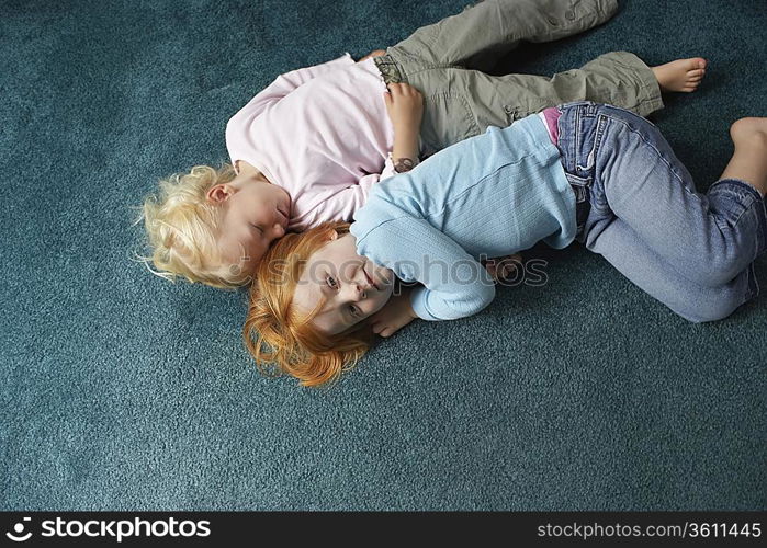 Sisters (3-6) lying on carpet one looking at camera view from above