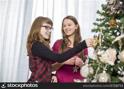 Sisters decorating on Christmas tree at home