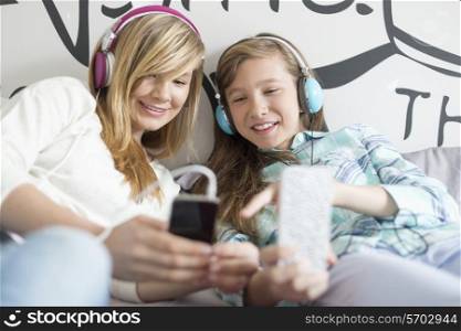 Sisters listening music through headphones at home