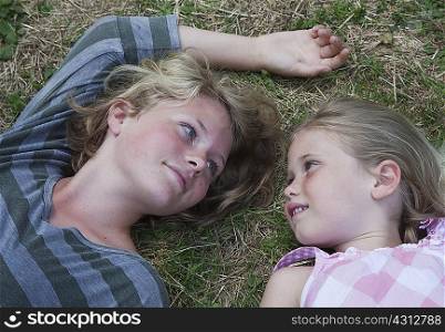 Sisters lying on grass, face to face