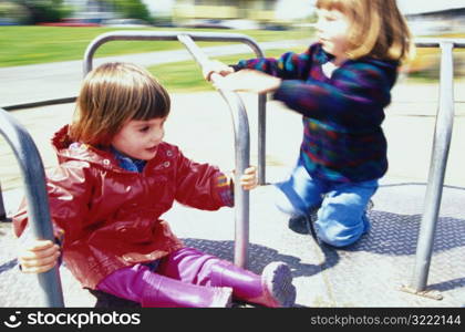 Sisters on Playground Merry Go Round
