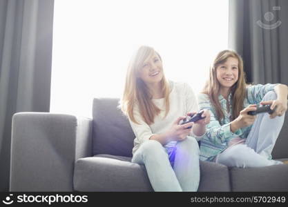 Sisters playing video games on sofa