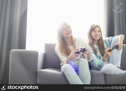 Sisters playing video games on sofa