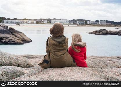sisters sitting near the sea the shore at the Tregastel, Brittany. France