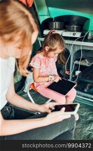 Sisters spending family time in a tent on c&ing. Children using tablet playing games online during summer vacation. Sisters spending time in a tent on c&ing. Children using tablet playing games online during summer vacation
