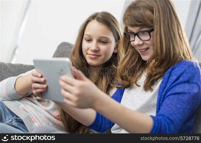 Sisters using digital tablet together at home