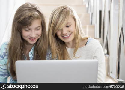 Sisters using laptop on stairway