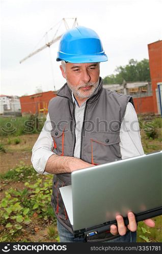 Site manager with laptop computer checking construction