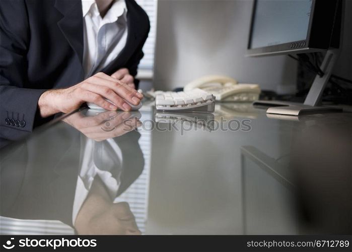 sitting at glass topped desk with computer