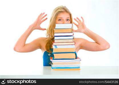 Sitting at table stressed young girl looking out of pile of book&#xA;