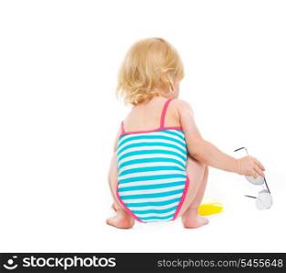 Sitting baby in swimsuit with sun glasses. Rear view